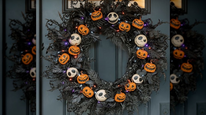 A skull and pumpkin wreath hanging from a front door
