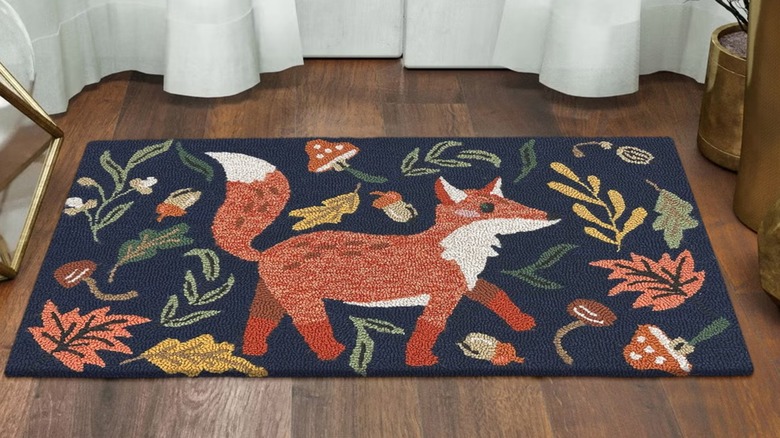 A merry-looking fox on a small rug placed on a wood floor