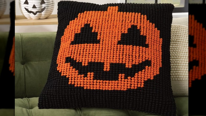 A black throw pillow with a pumpkin on top