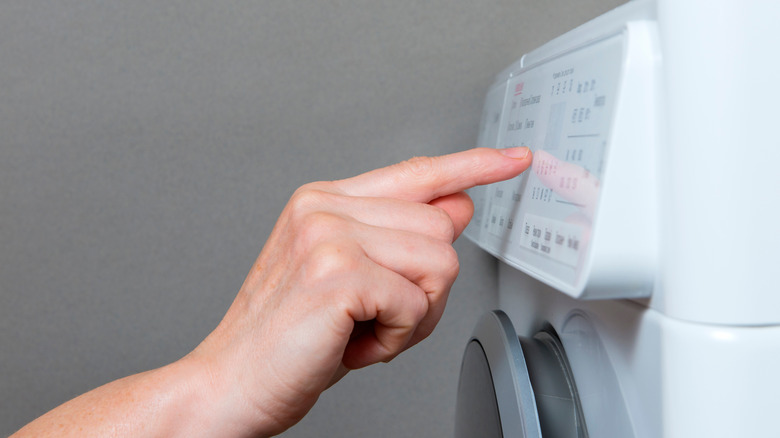 A person's hand selecting a cycle on a washing machine