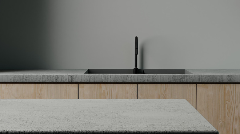 A gray kitchen with concrete countertops and light-colored wood