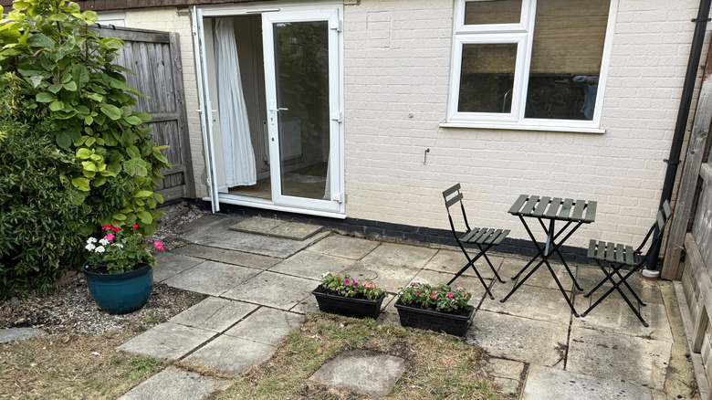 A cafe table and chairs sit on a dingy old concrete patio