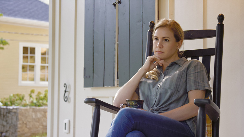 A woman sits on her porch in a rocking chair, deep in thought