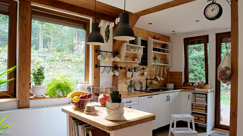 A rustic kitchen with a large open window with plants
