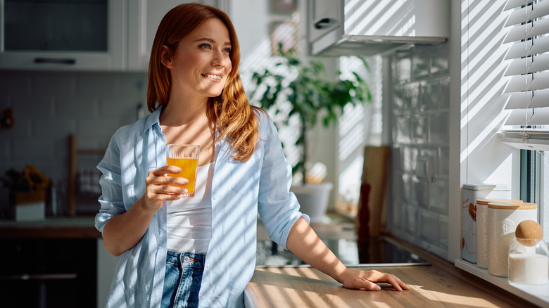 Woman standing in front of kitchen window with blinds