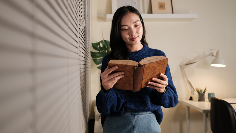 A young woman reads an antique, aged book