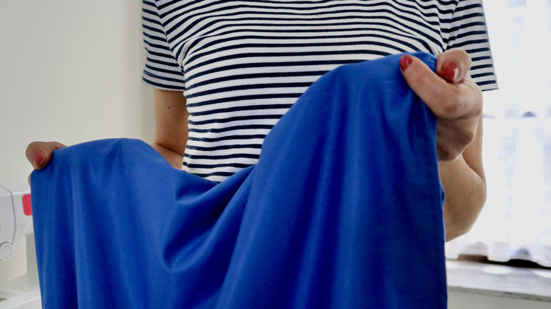 Woman with painted red nails holding blue velvet fabric