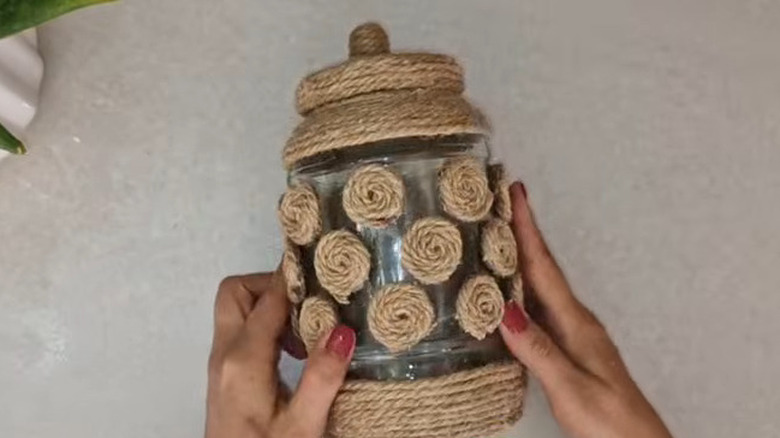 Person using hot glue to attach jute twine to a jar