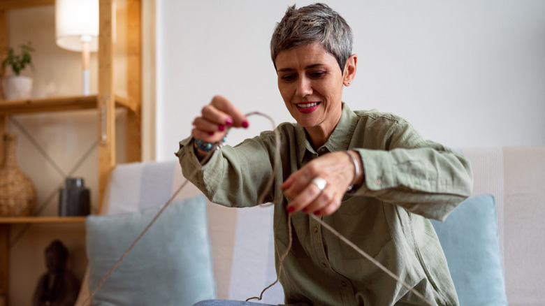 A woman prepares twine for a craft