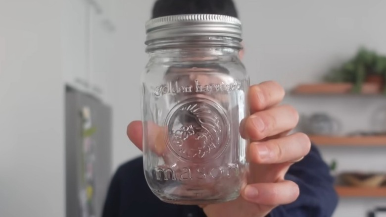 Close-up of person's hand holding an empty mason jar