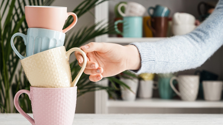 Woman's hand with assorted coffee mugs