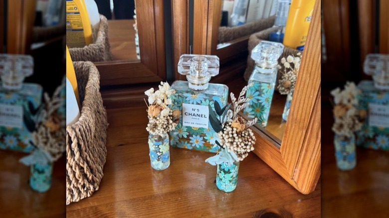 Painted blue floral perfume bottles on a dresser top, holding dried flowers.
