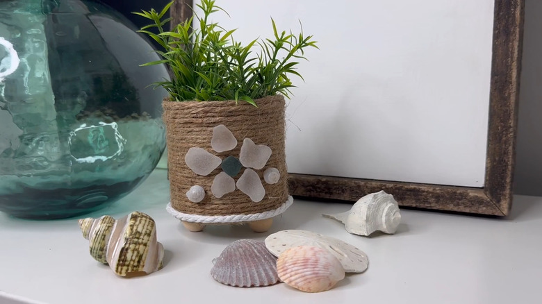 Upcycled can covered in twine with beach glass designs holding a faux plant