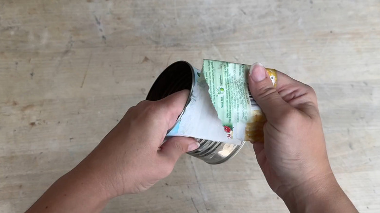 Person removing the label from a corn can to prep it for a DIY project