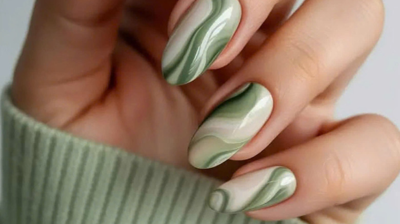 A close up fingernails painted with a marbled green design.