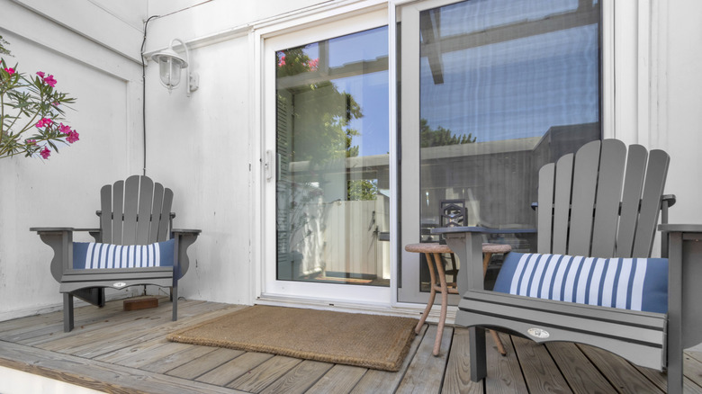 The exterior view of sliding glass doors with Adirondack chairs on either side