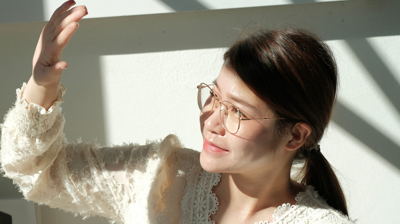 Asian woman indoors and shielding eyes from sunlight