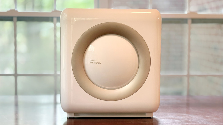 A Coway Airmega Mighty AP-1512HH sits on a wooden desk in front of an exterior window