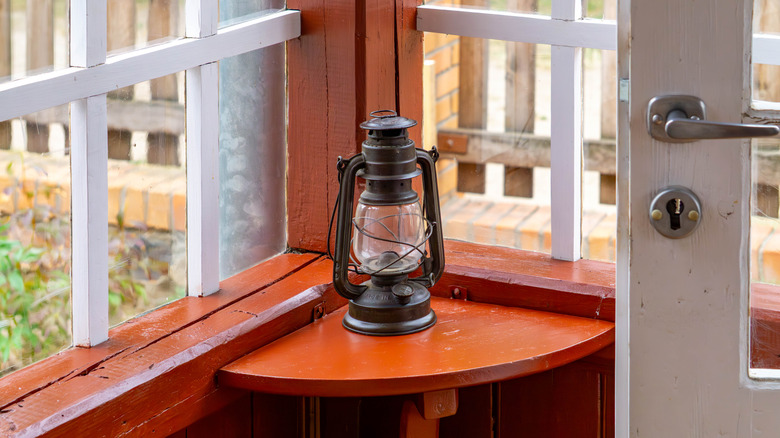 A vintage oil lantern on a red corner shelf