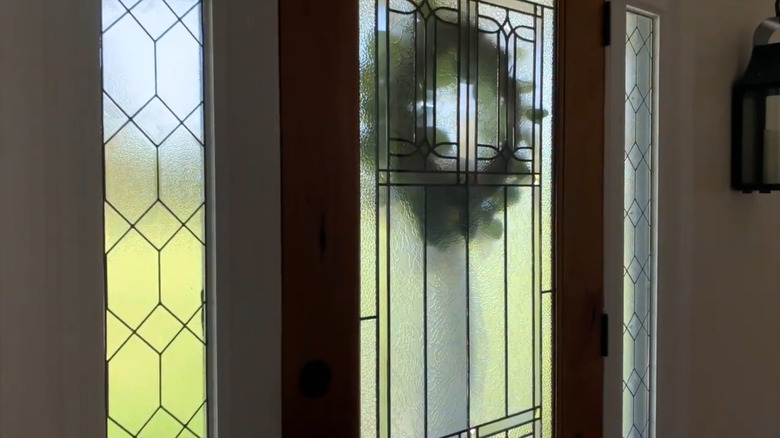 A front door with frosted window panes and a wreath outside