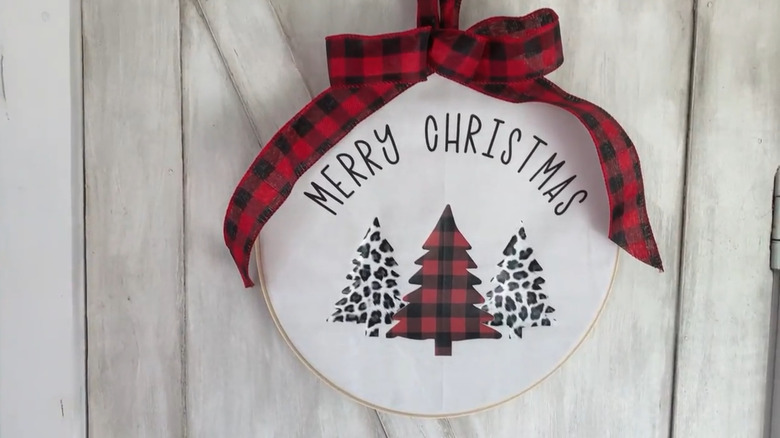 A door hanger made from an embroidery hoop with christmas trees and a ribbon