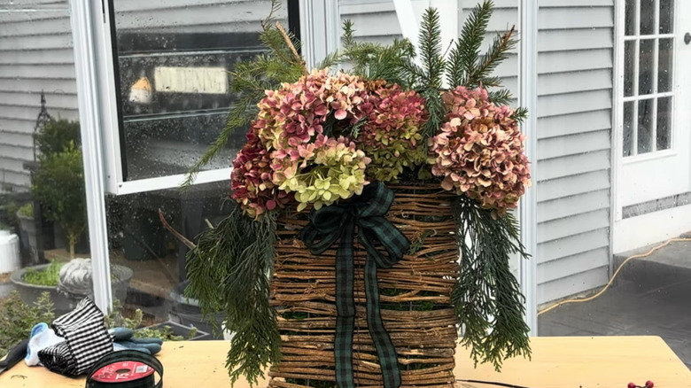 A basket full of pine branches and hydrangeas