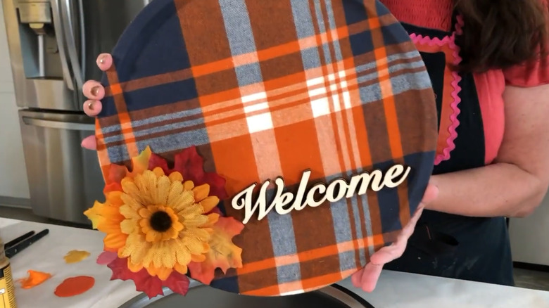Pizza pan covered in autumnal fabric with a fake flower and the word welcome
