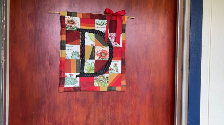 A quilted door hanging in fall colors with the letter D in the middle