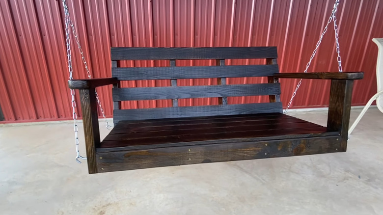 A porch swing made from wooden boards, hanging by chains