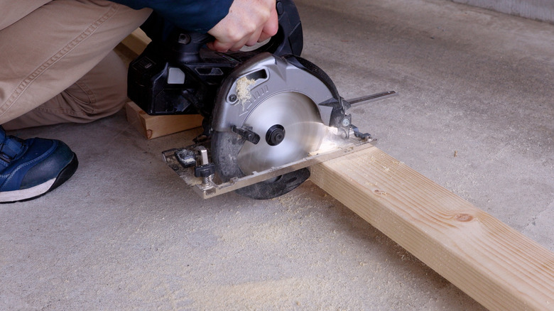 Person cutting through a 2x4 with a saw