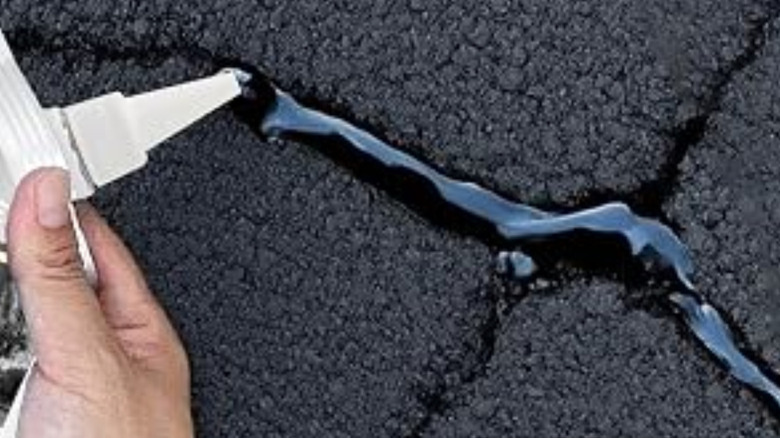 Filling a crack in asphalt driveway with flexible sealer