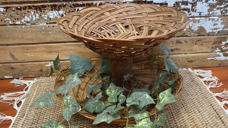 Two wicker baskets with a candle holder between to make a tiered tray