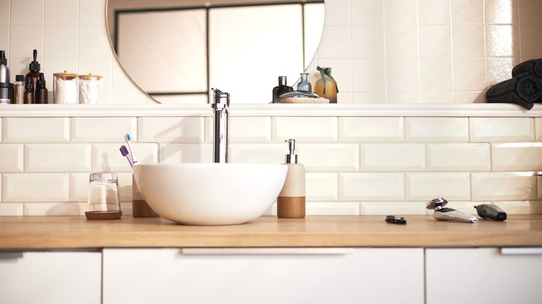 Modern bathroom sink and counter with various grooming equipment and accessories