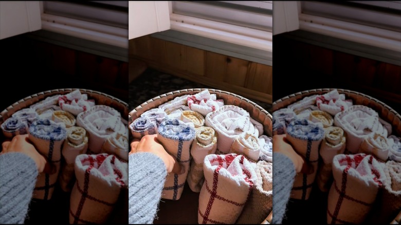 hand placing rolled towels in bowl