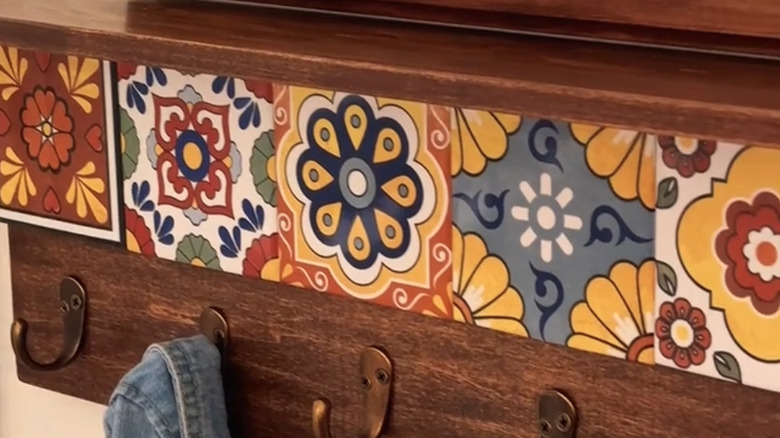 Close-up of an entryway shelf with brass hooks and Talavera tiles