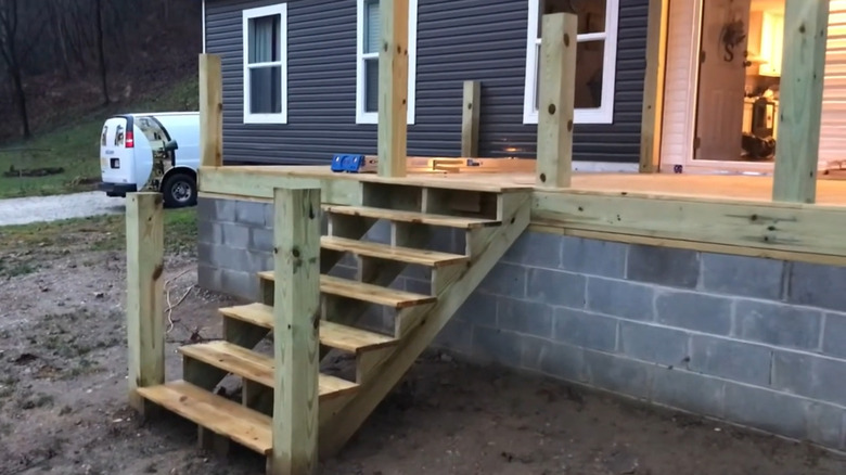 A porch with a concrete block base, wooden top, and wooden stairs