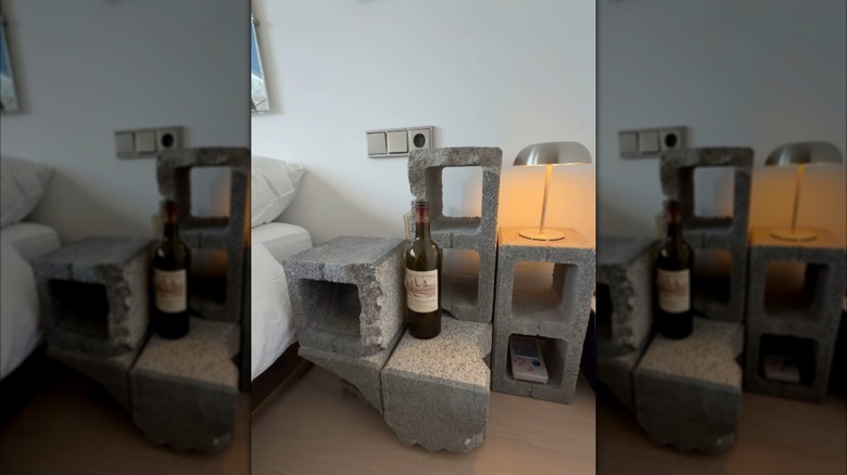 A nightstand made of concrete blocks with a lamp and wine bottle on top