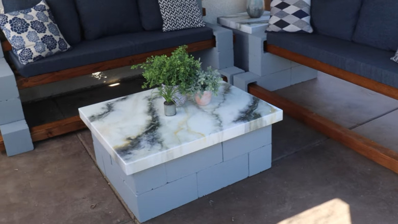 A low concrete block table with a marbled top between two couches