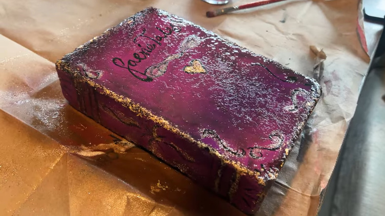 A concrete block painted like a purple fairy tale book