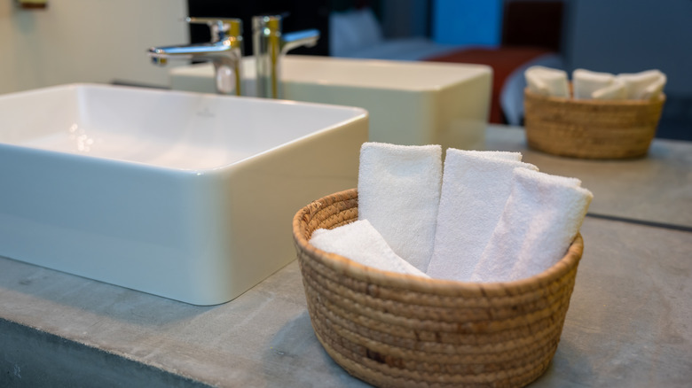 Rolled hand towels in woven basket on bathroom counter
