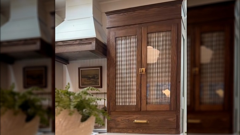 Warm wood glass cabinet with plaid drapes in window