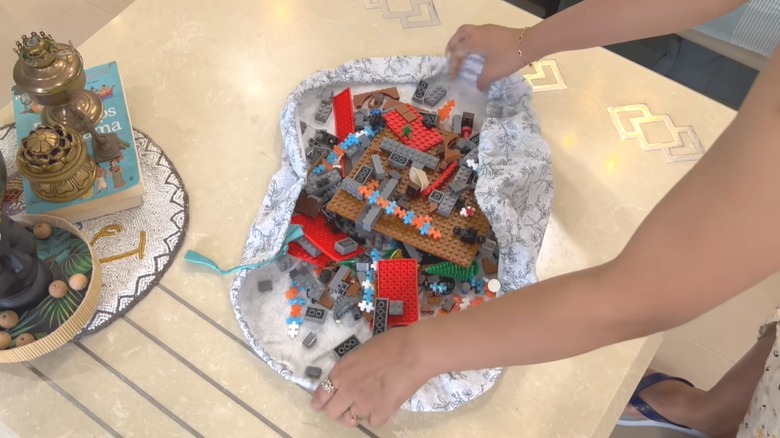 Woman storing Legos in stylish flower bag made from curtain material