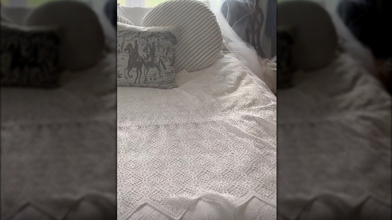 Lacey curtain used as bed throw in white classic-style bedroom