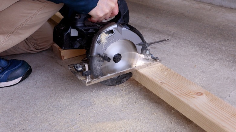 Person cross-cutting 2-by-4 board with circular saw