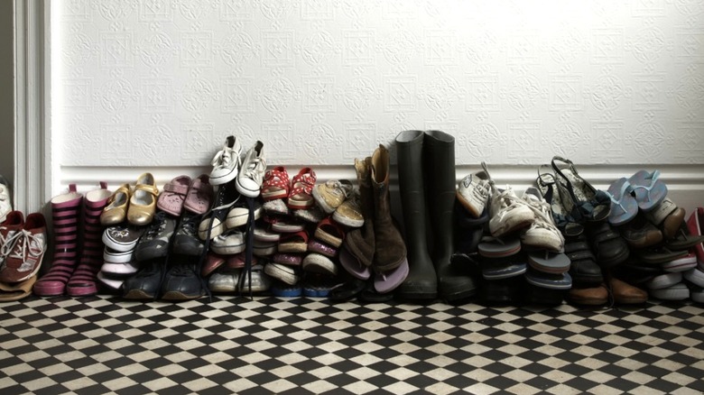 Piles of shoes and boots on the floor by a wall