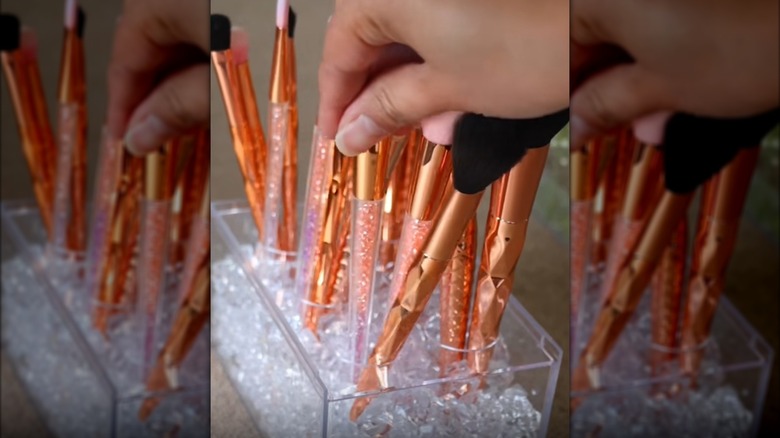 Person arranging makeup brushes in a Dollar Tree flower container