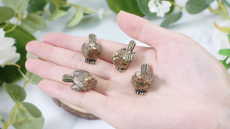 hand holding copper bird figurines