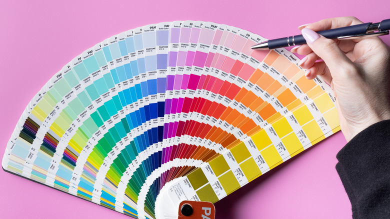 person picking out a shade of pink from a Pantone color swatch deck