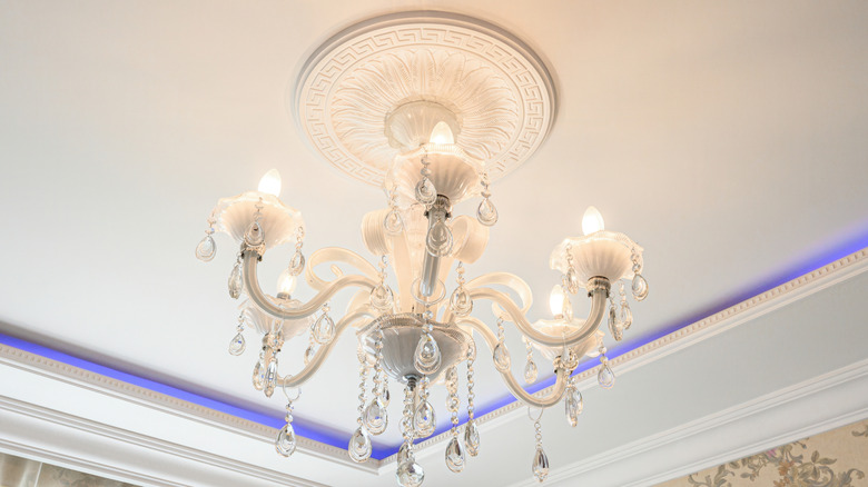 A crystal chandelier hanging from the ceiling with a medallion