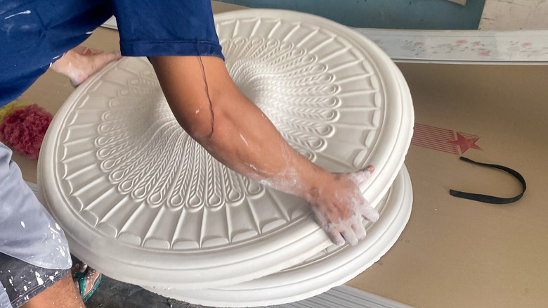 A person picking up a ceiling medallion for installation